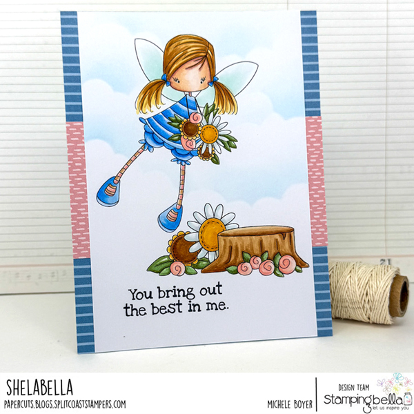 Handmade greeting card featuring Stamping Bella Whimsabella GlimmerGlade, Spring Backdrop, and Spec-Tacular Together Sentiment Set cling mounted rubber stamps. The whimsical scene is colored with Copic alcohol markers and showcases a fairy with pigtails and wings, holding a bouquet of flowers and flying. The background includes a tree stump, flowers, and greenery, and subtle ink blended clouds. The sentiment 'You bring out the best in me.' is stamped at the bottom of the card. The card is bordered with blue and pink patterned strips. Designed by Michele Boyer, part of the Stamping Bella Design Team.