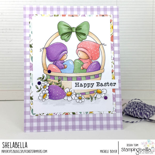 Handmade Easter greeting card featuring Stamping Bella Bundle Girls in the Easter Basket cling mounted rubber stamp. The card showcases two adorable girls in purple and pink hooded outfits sitting in a woven basket filled with colorful Easter eggs. The basket is adorned with a large green bow at the top and surrounded by purple Easter eggs and white daisies. The card has a 'Happy Easter' sentiment and is framed with a purple gingham pattern and floral border. The design is by Michele Boyer for the Stamping Bella design team.