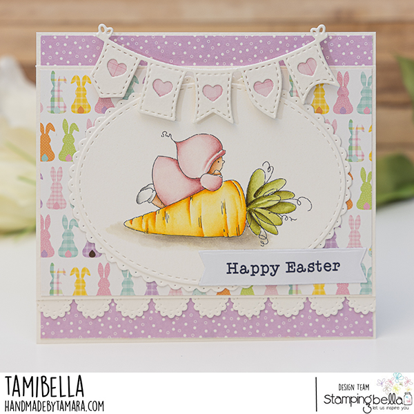 Handmade Easter greeting card featuring a Stamping Bella Bundle Girl with a Carrot cling mounted rubber stamp. The card has a pastel color scheme with a background of multicolored bunny silhouettes and a purple polka dot pattern. The central image shows a small girl in a pink outfit hugging a large orange carrot with green leaves. Above the image is a banner with heart cutouts. The card includes a 'Happy Easter' sentiment on a white banner. The card is designed by Tamara for Stamping Bella.